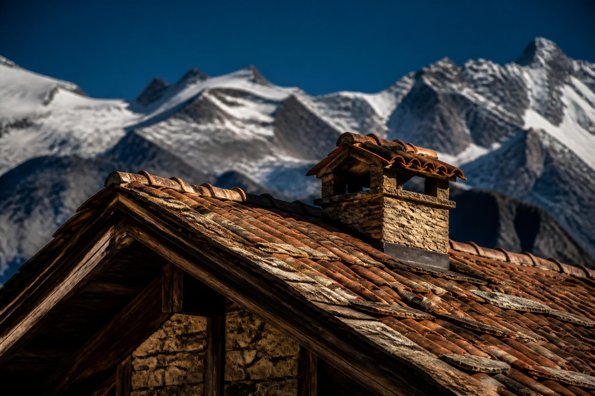 Toiture de chalet alpin en tuiles traditionnelles face aux sommets enneigés